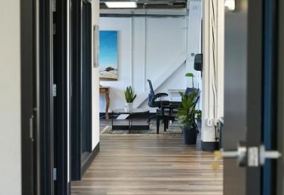 Modern hallway with wood-style flooring leading to open office spaces and creative artwork.