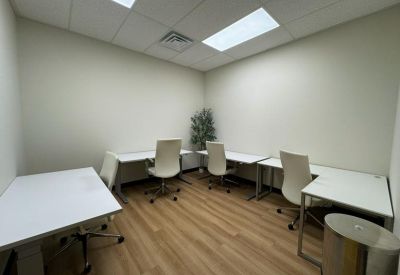 Internal four-person office suite with white desks and a potted plant.