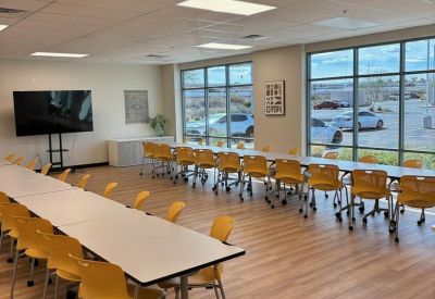 Large training room with yellow chairs and rows of modular white tables.
