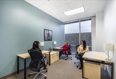 Internal three-person office suite with blue accent wall and large window.