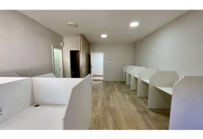 Open-plan coworking area with white dividers and light wood flooring.