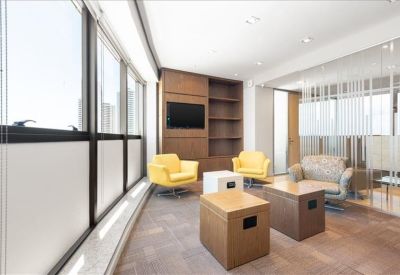 Modern lounge area with yellow armchairs, a television, and large windows.