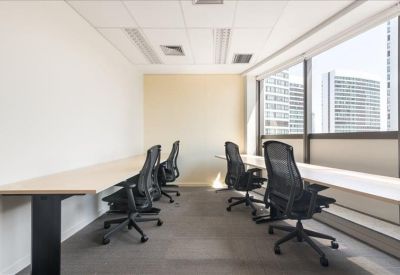 Long workstation desk with ergonomic chairs positioned along a large window.