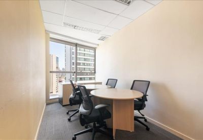 Small private meeting room with a round table, four mesh chairs, and city views.