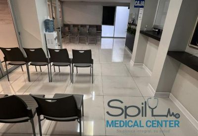 Patient waiting area with rows of black chairs and a reception counter.