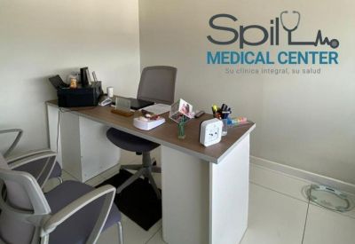 Consultation office with a wooden desk and medical equipment.