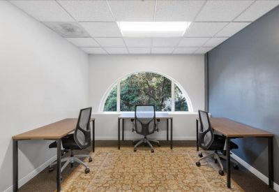 Private office for three with arched window and patterned carpet.