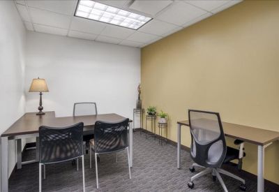 A two-person office suite featuring an L-shaped desk and yellow accent wall.
