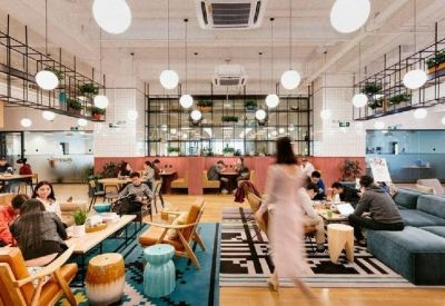 Large communal lounge with tiered seating, blue velvet sofas, and numerous spherical pendant lights.