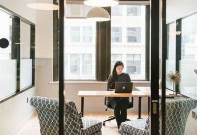 Private glass-walled office suite with a wooden desk and patterned armchairs.