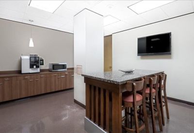 Modern kitchen and break area with a wood island, bar stools, and coffee machine.