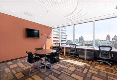 Private office with a wood desk, green accent wall, and large corner windows.