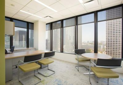 Professional glass-walled meeting room with potted plants and seating area.
