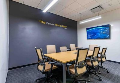 Professional boardroom with a long wooden table, black-framed chairs, and an accent wall.