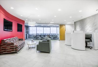 Spacious reception lobby with a red curved wall, comfortable seating, and a view into a meeting area.
