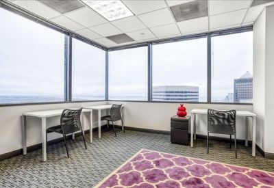 Three-person private office with individual desks and large windows overlooking the city.
