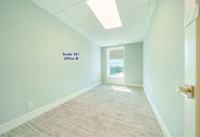 Bright private office featuring a single window and modern overhead lighting.