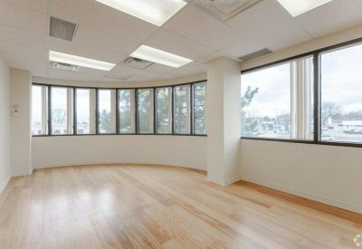 Large office suite with a curved wall of windows and light wood-look flooring.