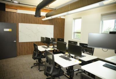 Modern coworking space with multiple computer monitors and a large whiteboard.