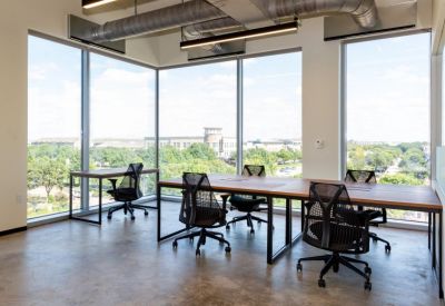 Bright corner office with wooden desks and ergonomic chairs overlooking the city.