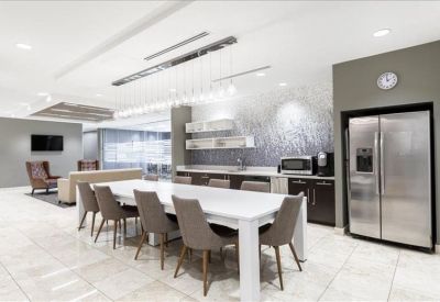 Modern communal kitchen and dining area with stainless steel appliances and pendant lighting.