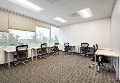 Bright shared office space with multiple workstations and large windows.
