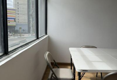 Minimalist meeting room with a white table and large windows overlooking the city.