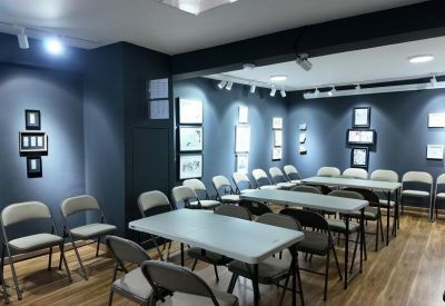 Modern conference room with dark walls, art displays, and multiple folding tables.