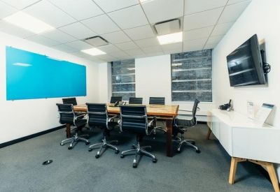 Bright conference room with a blue glass whiteboard and views of the city skyline.