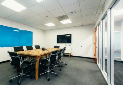 Professional meeting room with a large wooden table, black leather chairs, and a monitor.
