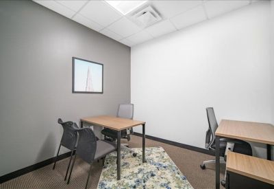 Three-person private office with wooden desks and a grey accent wall.