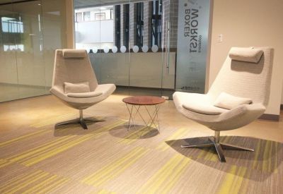 Lounge area with two modern cream-colored armchairs and a small side table.