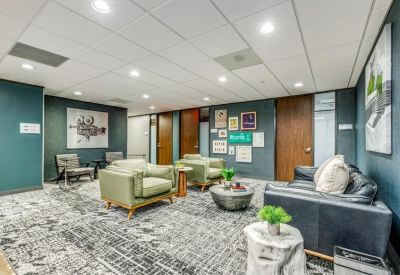 Casual waiting area featuring green armchairs and a dark leather sofa.