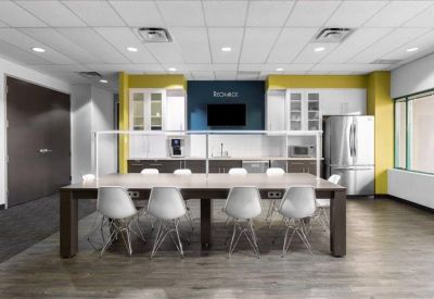 Modern communal kitchen and breakout area with yellow accent walls and a large dining table.