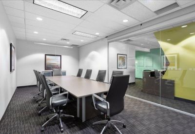 Spacious boardroom with a large wooden table and comfortable black leather chairs.