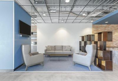 Modern lounge area with a grey sofa, stylish armchairs, and a decorative wooden bookshelf.