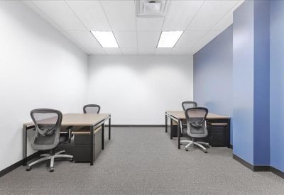 Interior office suite with two separate desks and ergonomic chairs against a blue accent wall.