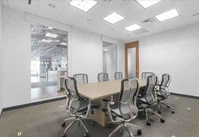 Meeting room with a long wooden table and mesh chairs next to a glass wall.
