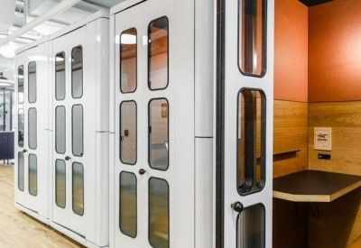 Sleek white privacy phone booths and a built-in workspace alcove.
