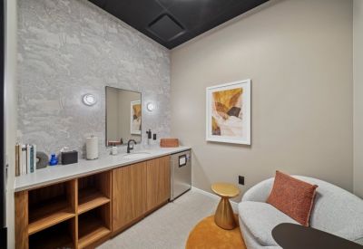 Private lounge area with wood cabinetry, tree-patterned wallpaper, and a plush armchair.