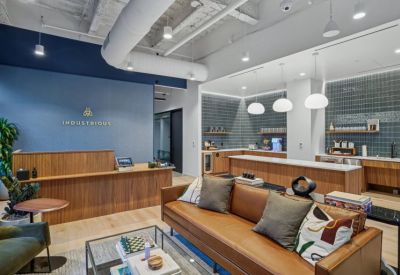 Branded reception desk with wood paneling and a modern kitchen area with white pendant lights.