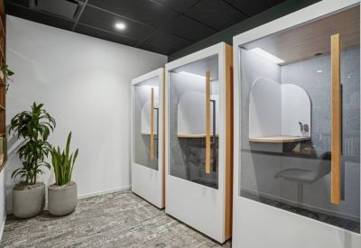 Private phone booths with glass doors and wood accents in a modern workspace.
