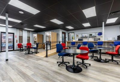 Spacious coworking area with red and blue chairs and a black industrial ceiling.