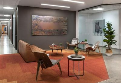 Modern communal lounge area featuring an orange geometric rug, leather sofa, and stylish mid-century chairs.