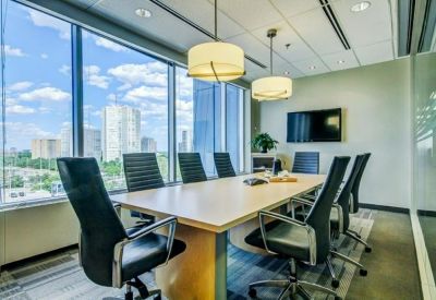 Meeting room with a large table, black leather chairs, and expansive city views through floor-to-ceiling windows.