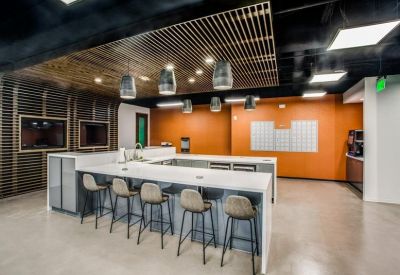 Bright communal kitchen and breakout area with an orange accent wall and white island.