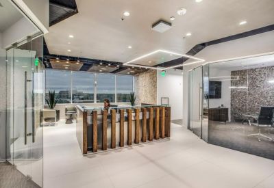 Modern reception area with a wood-slat desk and glass-walled offices.