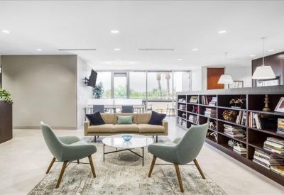 Modern lounge area with grey armchairs, a tan sofa, and a large dark wood bookshelf.
