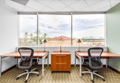 Shared office suite with two desks and a large window overlooking desert landscapes.