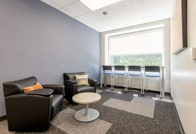 Lounge area with black armchairs and a high counter by the window.